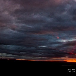 Zum Abschluss der Nacht zieht Bewölkung auf und die Sonne zeigt sich glühend rot